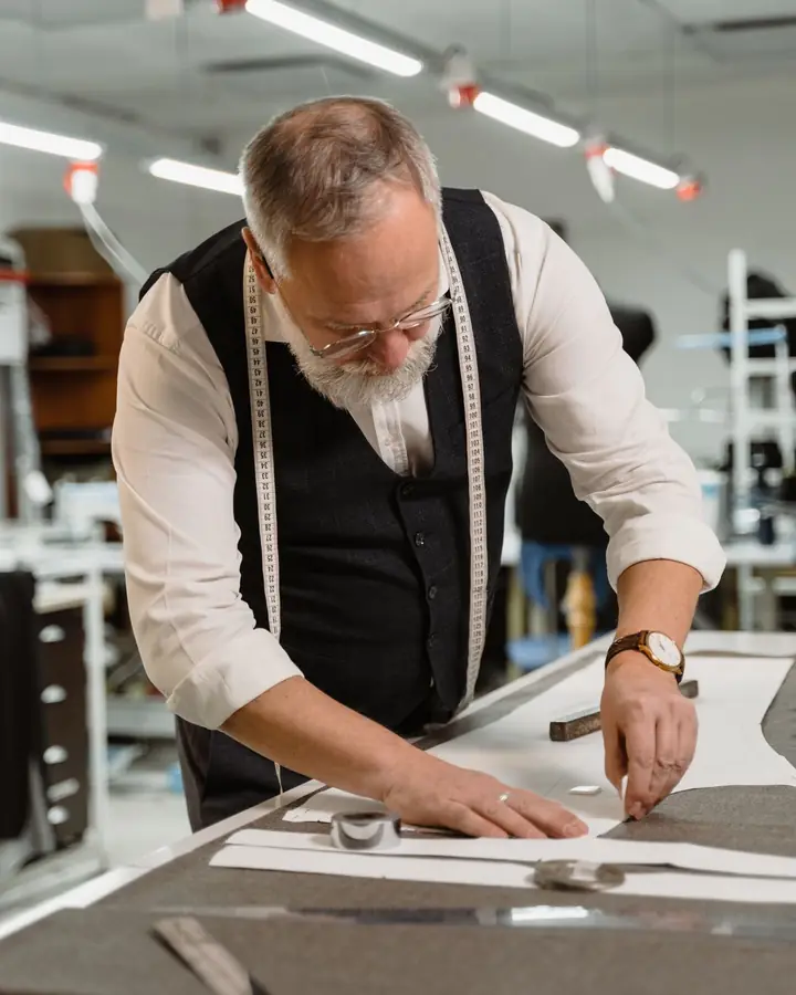 A tailor measuring cloth at a work table